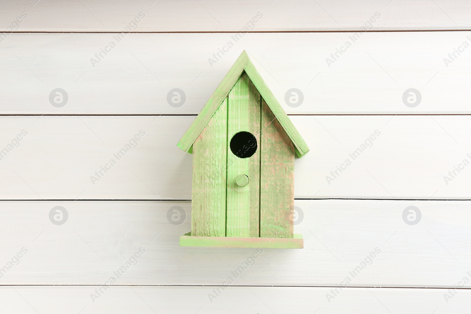 Photo of Beautiful green bird house on white wooden background