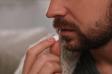 Man taking antidepressant pill on blurred background, closeup