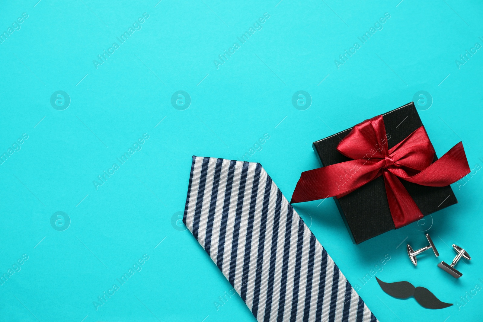 Photo of Gift box, cufflinks, necktie and paper mustache on light blue background, flat lay with space for text. Father's day celebration