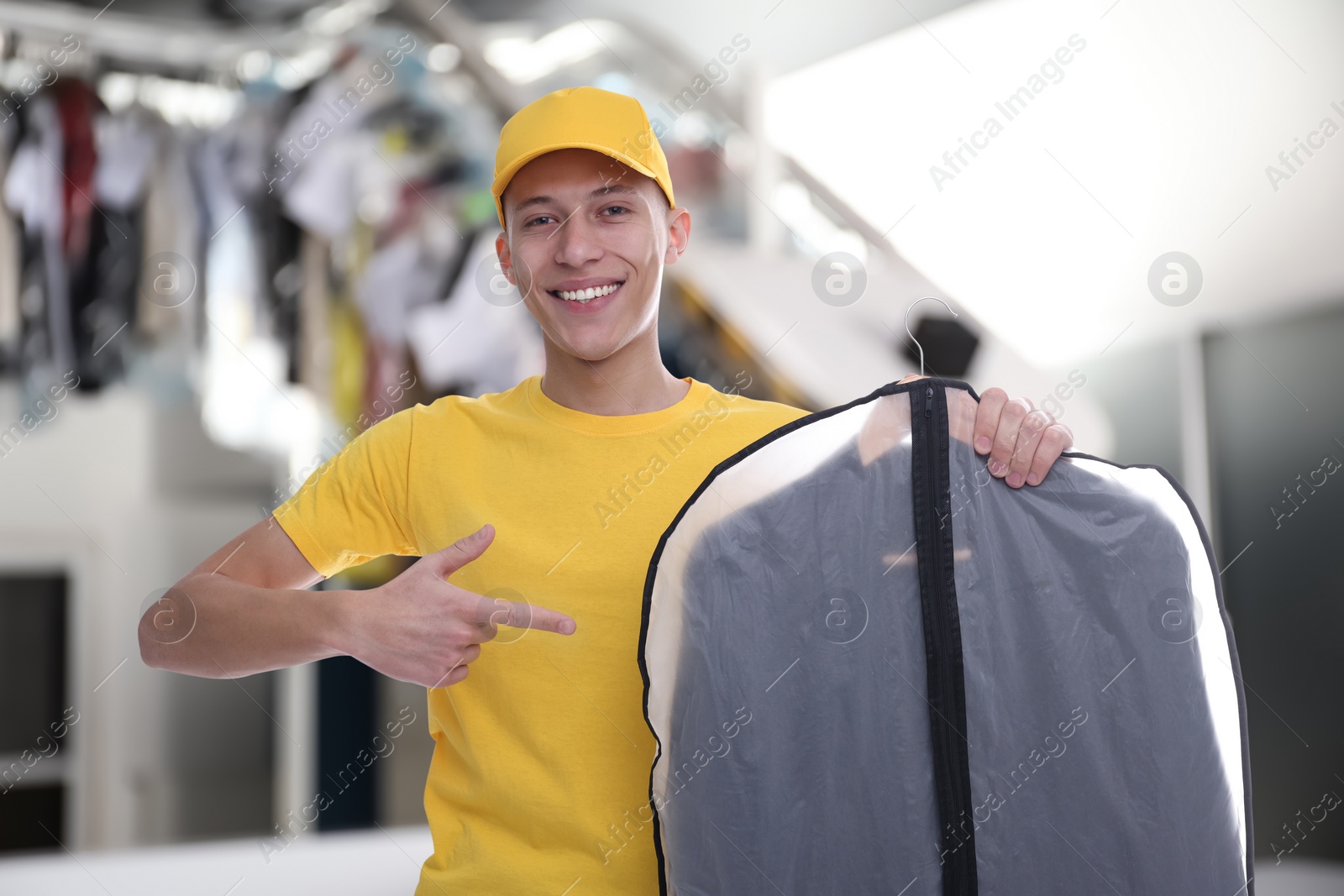 Image of Happy courier pointing at garment cover with clothes in dry-cleaning