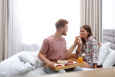 Photo of Happy young couple having romantic breakfast on bed at home