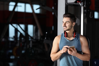Young man with headphones and mobile device at gym