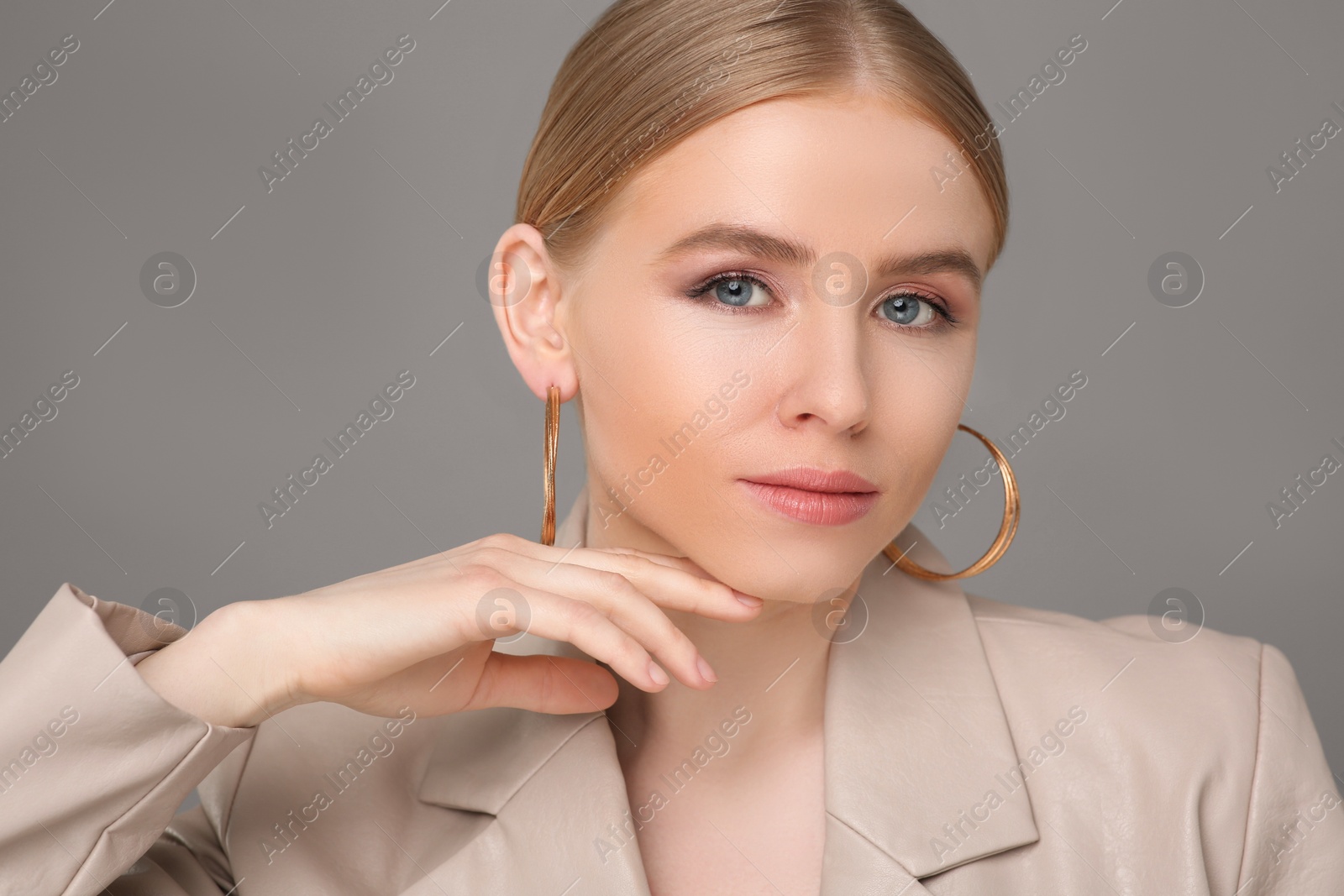 Photo of Beautiful young woman with elegant earrings on gray background