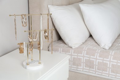 Photo of Holder with set of luxurious jewelry on nightstand in bedroom, space for text