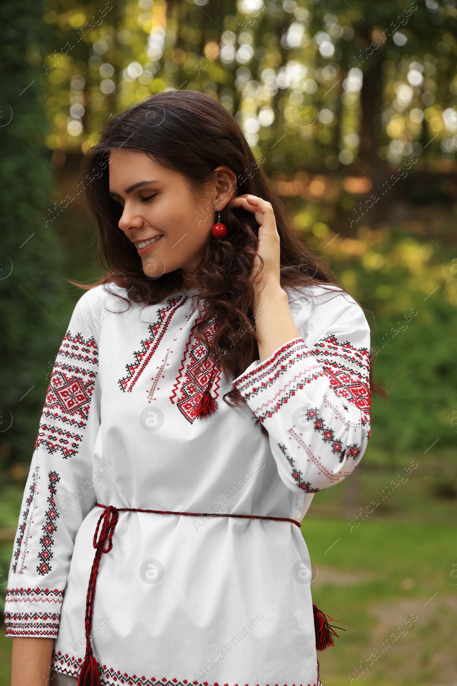 Photo of Beautiful woman in embroidered shirt outdoors. Ukrainian national clothes