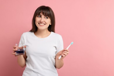 Photo of Young woman with mouthwash and toothbrush on pink background, space for text