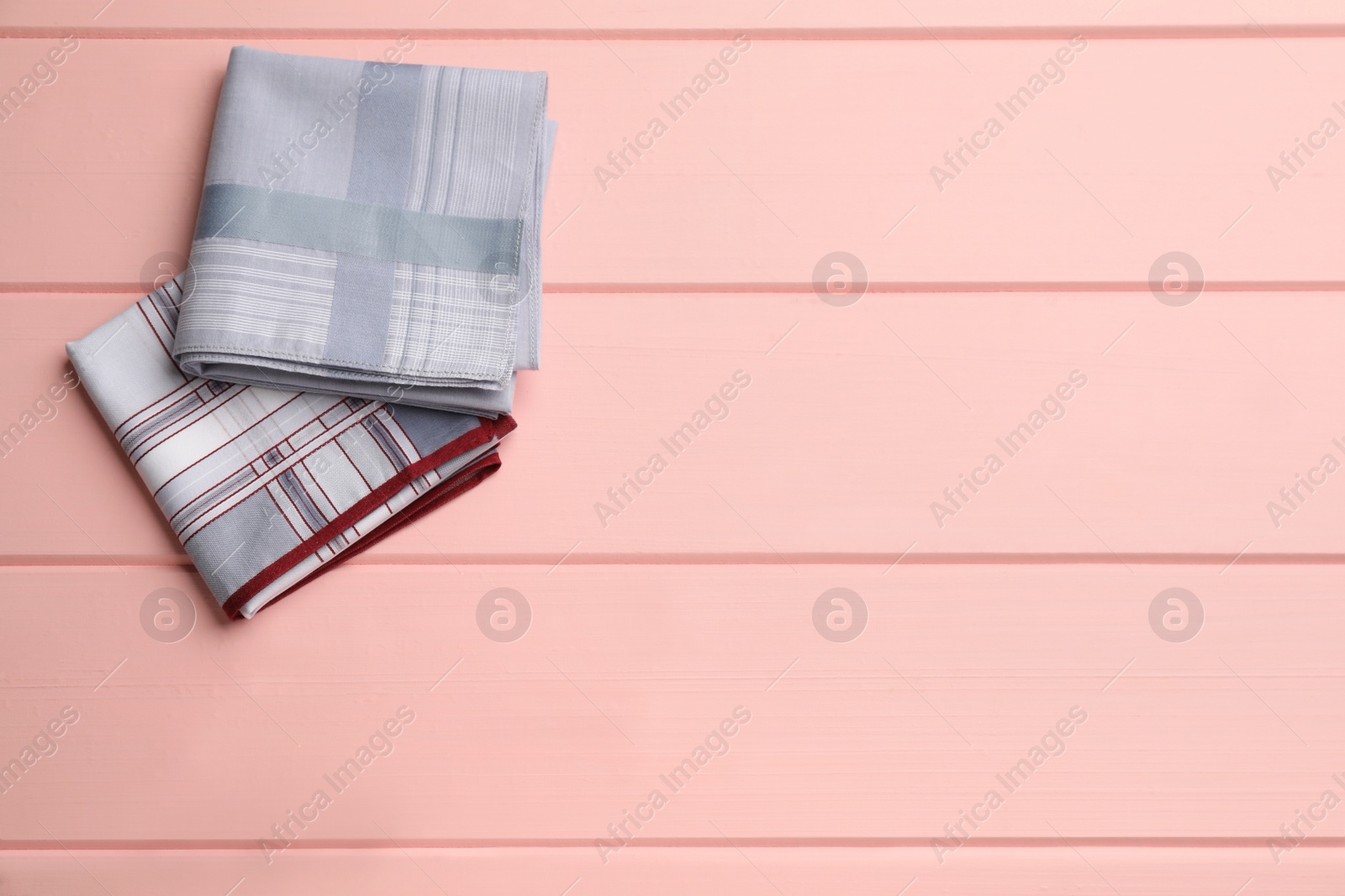 Photo of Different handkerchiefs folded on pink wooden table, flat lay. Space for text