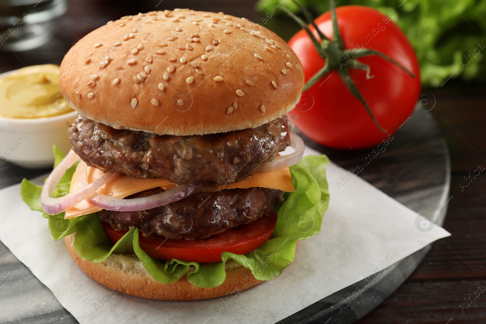 Photo of Tasty hamburger with patties, cheese and vegetables on wooden table, closeup