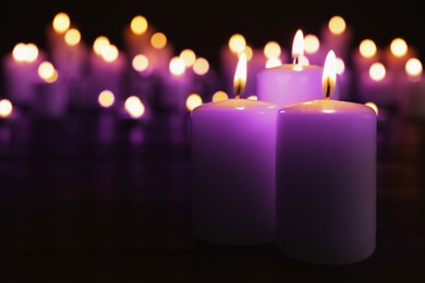 Image of Burning violet candles in darkness, space for text. Funeral attributes