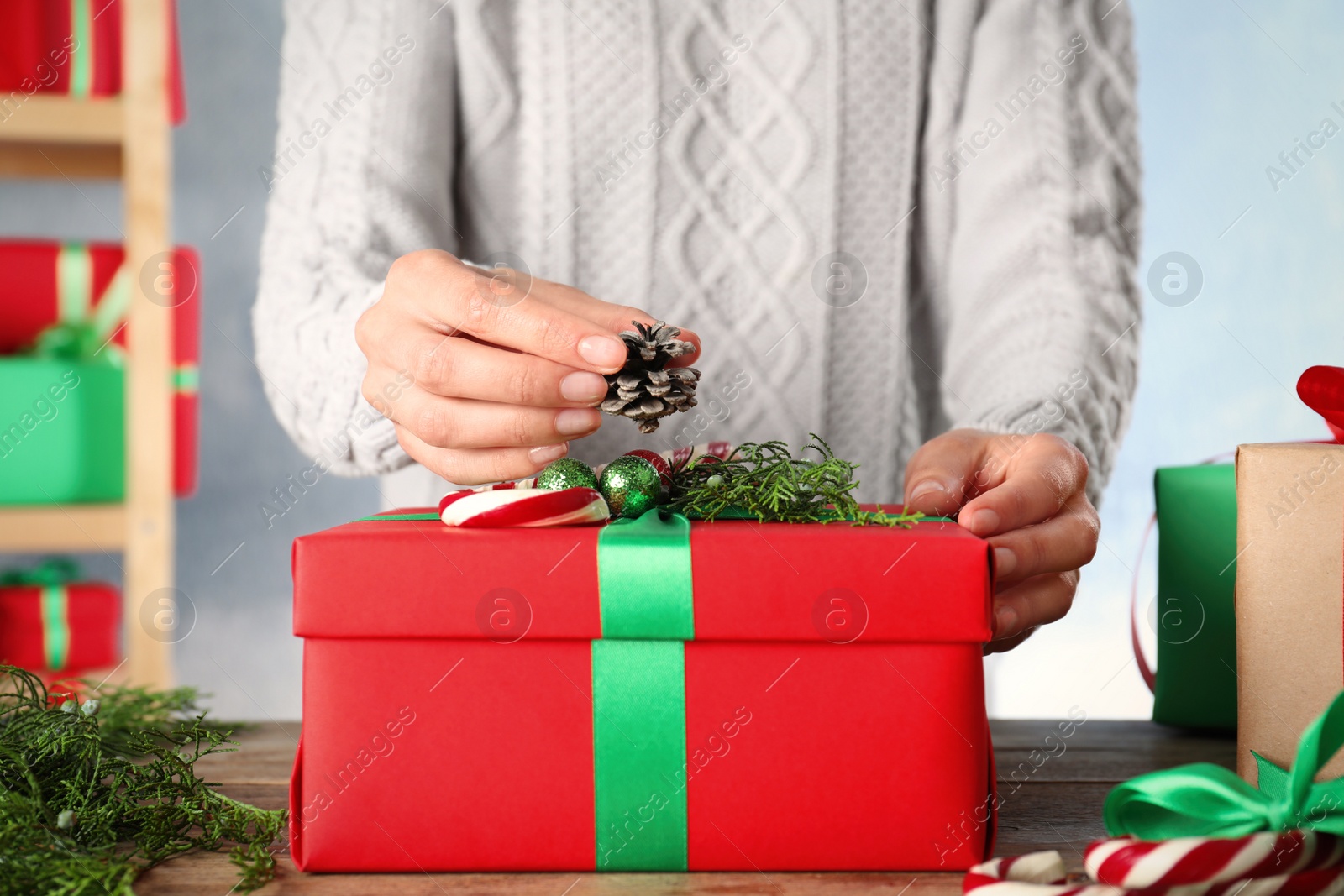 Photo of Woman wrapping Christmas gift at wooden table indoors, closeup