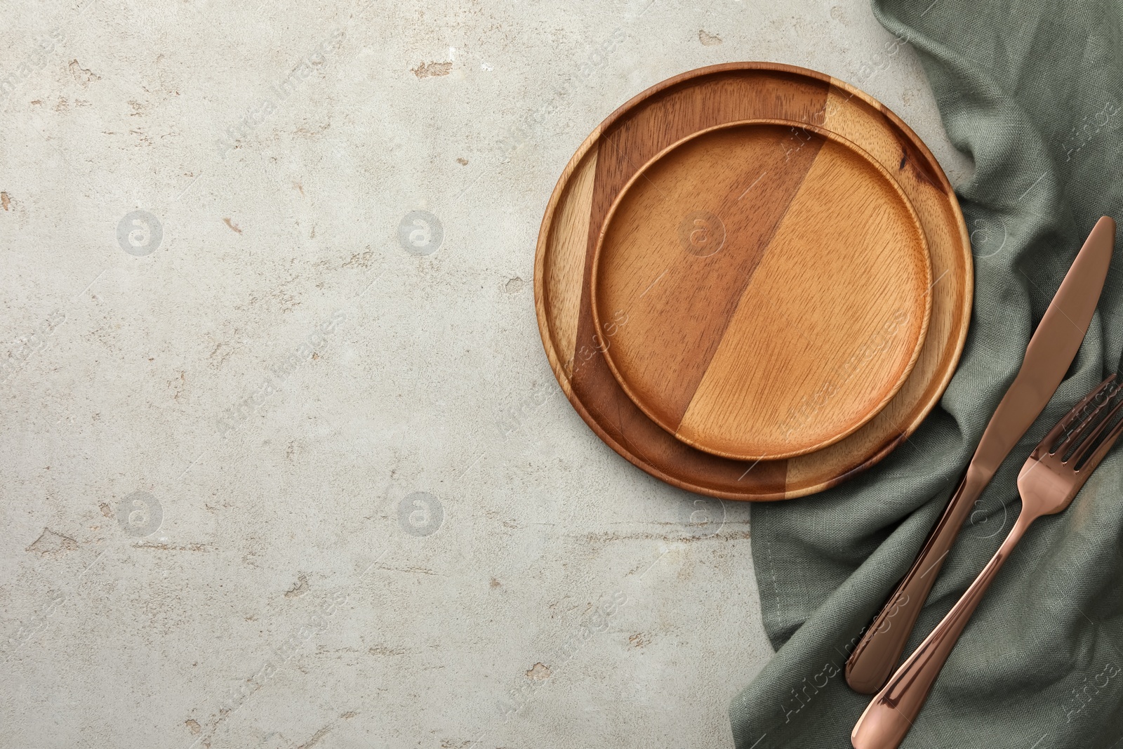 Photo of Stylish setting with cutlery, napkin and plates on light table, top view. Space for text