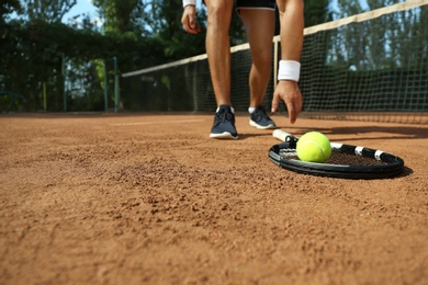 Photo of Sportsman playing tennis at court on sunny day, closeup