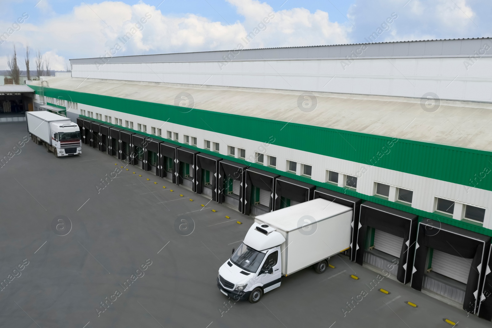 Image of Trucks near big warehouse outdoors, aerial view. Logistics center