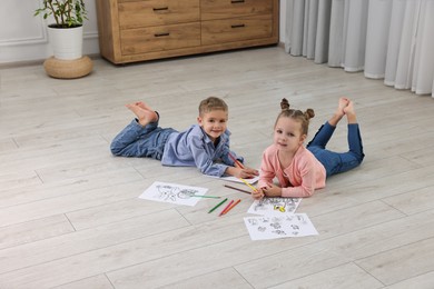 Photo of Cute little children coloring on warm floor at home. Heating system