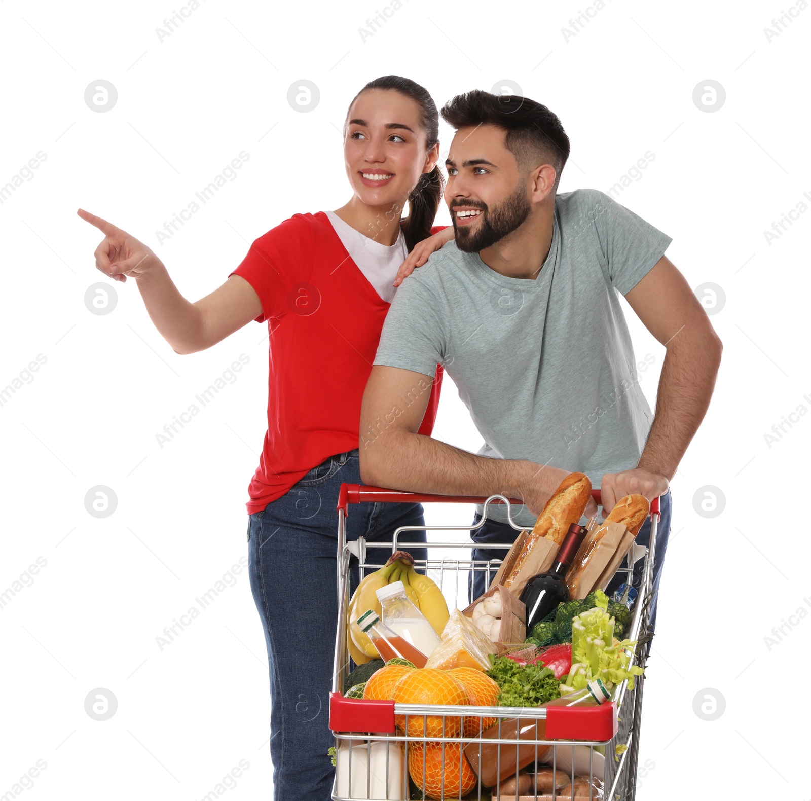 Photo of Happy couple with shopping cart full of groceries on white background