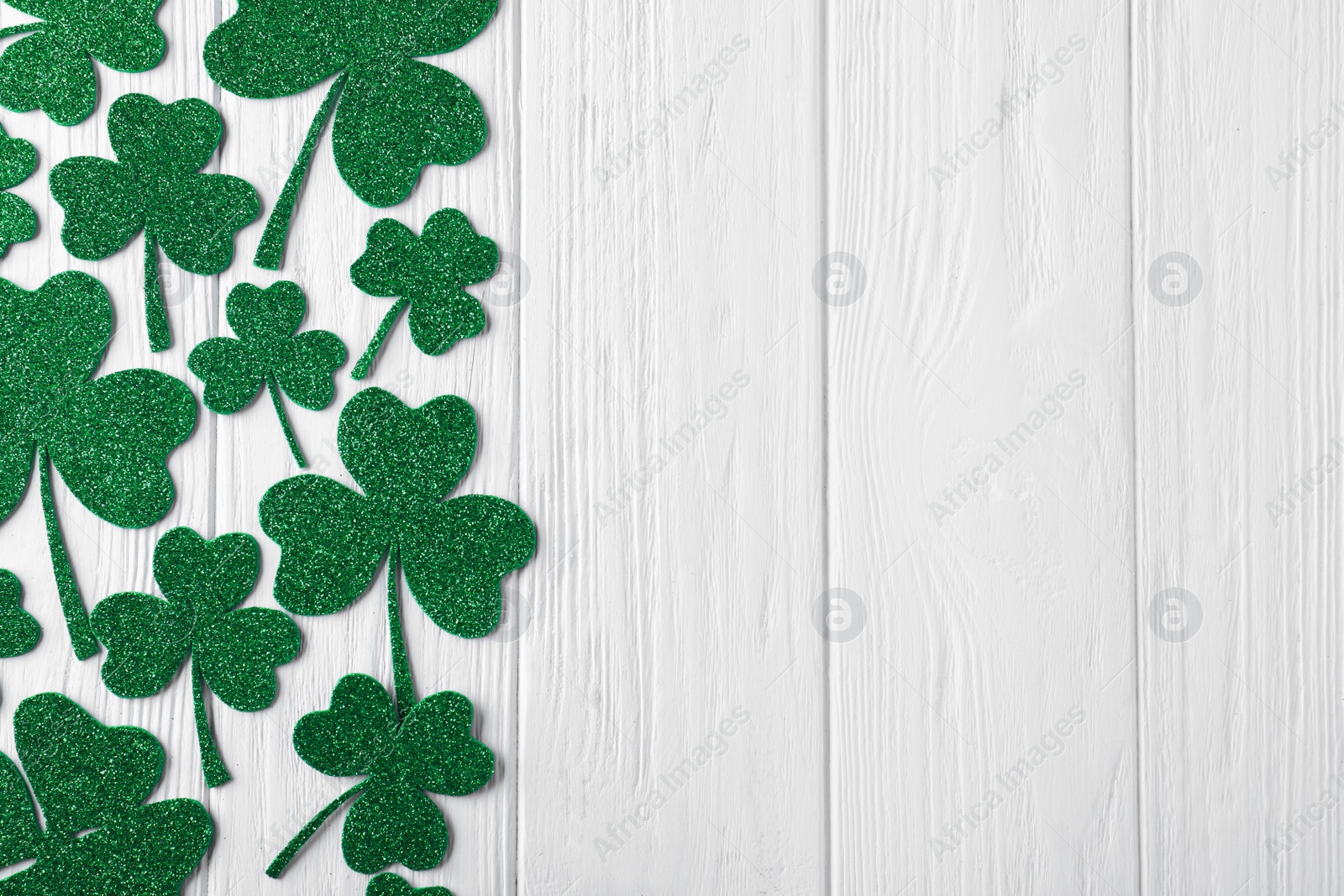 Photo of Flat lay composition with clover leaves on white wooden table, space for text. St. Patrick's Day celebration