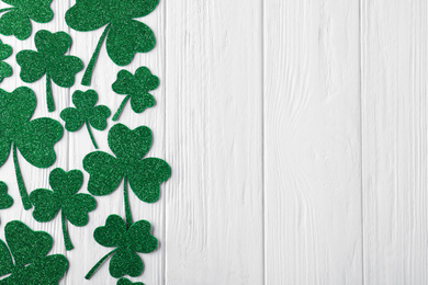 Flat lay composition with clover leaves on white wooden table, space for text. St. Patrick's Day celebration