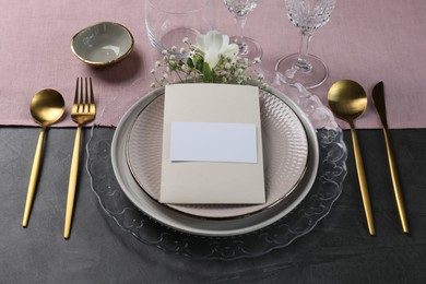 Photo of Stylish table setting. Dishes, cutlery, blank card and floral decor