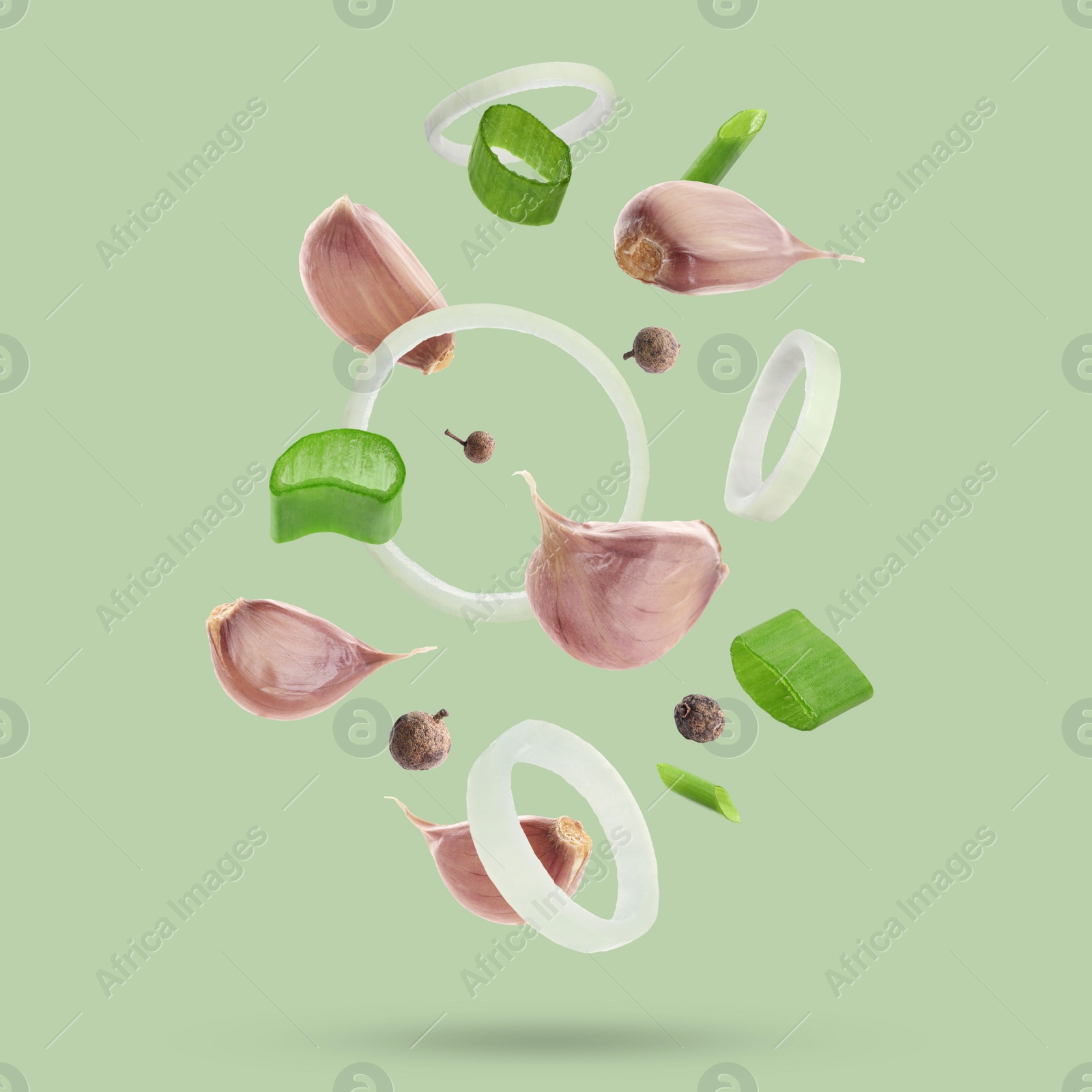 Image of Different spices falling on light green background