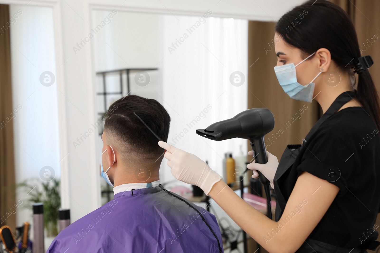 Photo of Professional stylist working with client in salon. Hairdressing services during Coronavirus quarantine