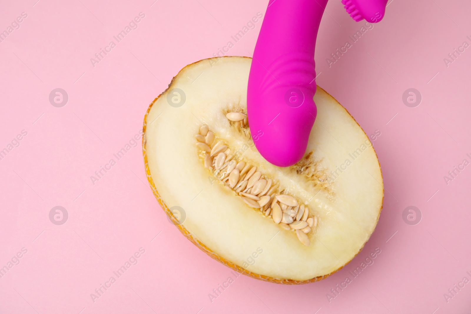 Photo of Half of melon and purple vibrator on pink background, flat lay. Sex concept