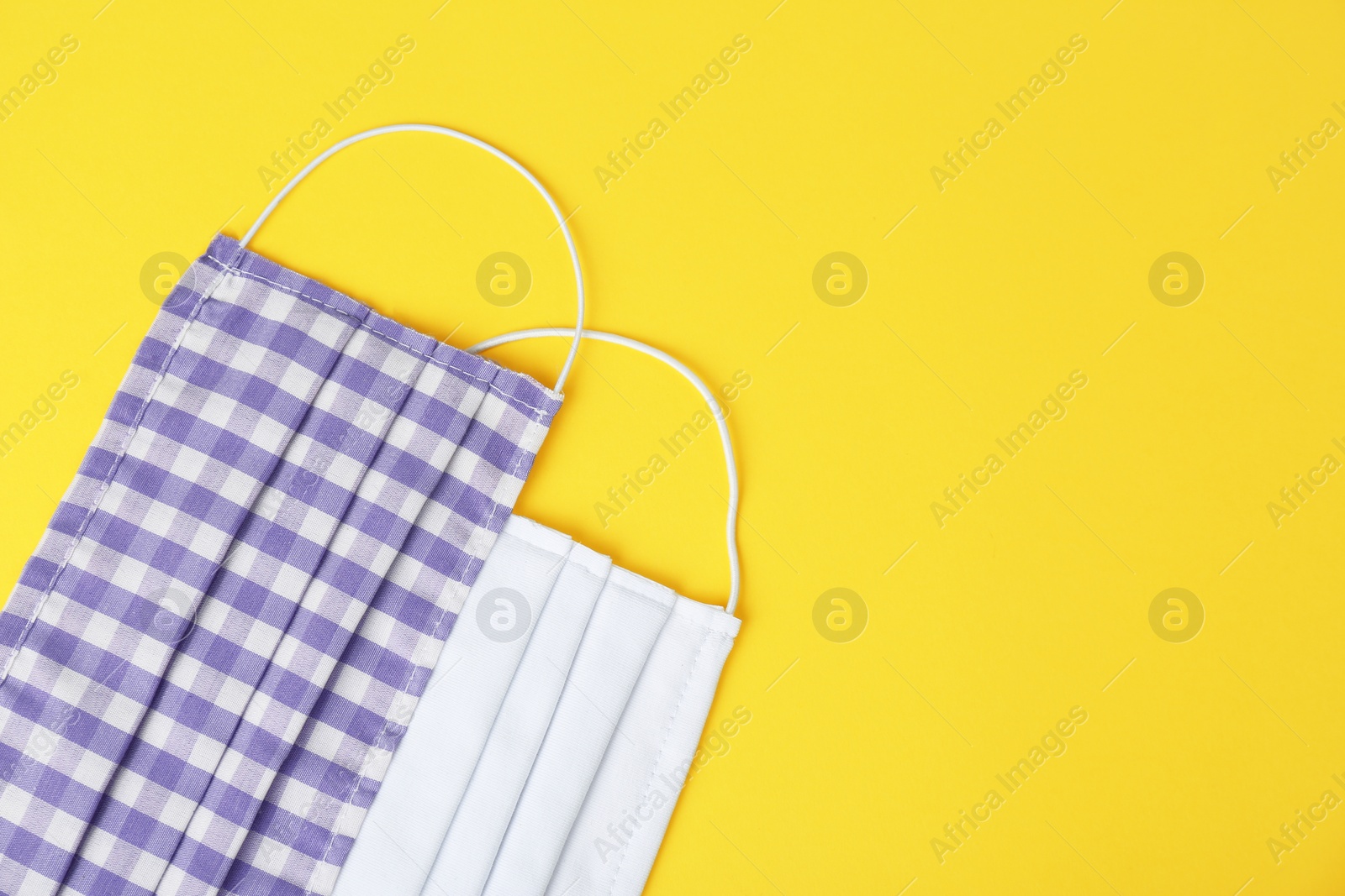 Photo of Homemade protective face masks on yellow background, flat lay. Space for text