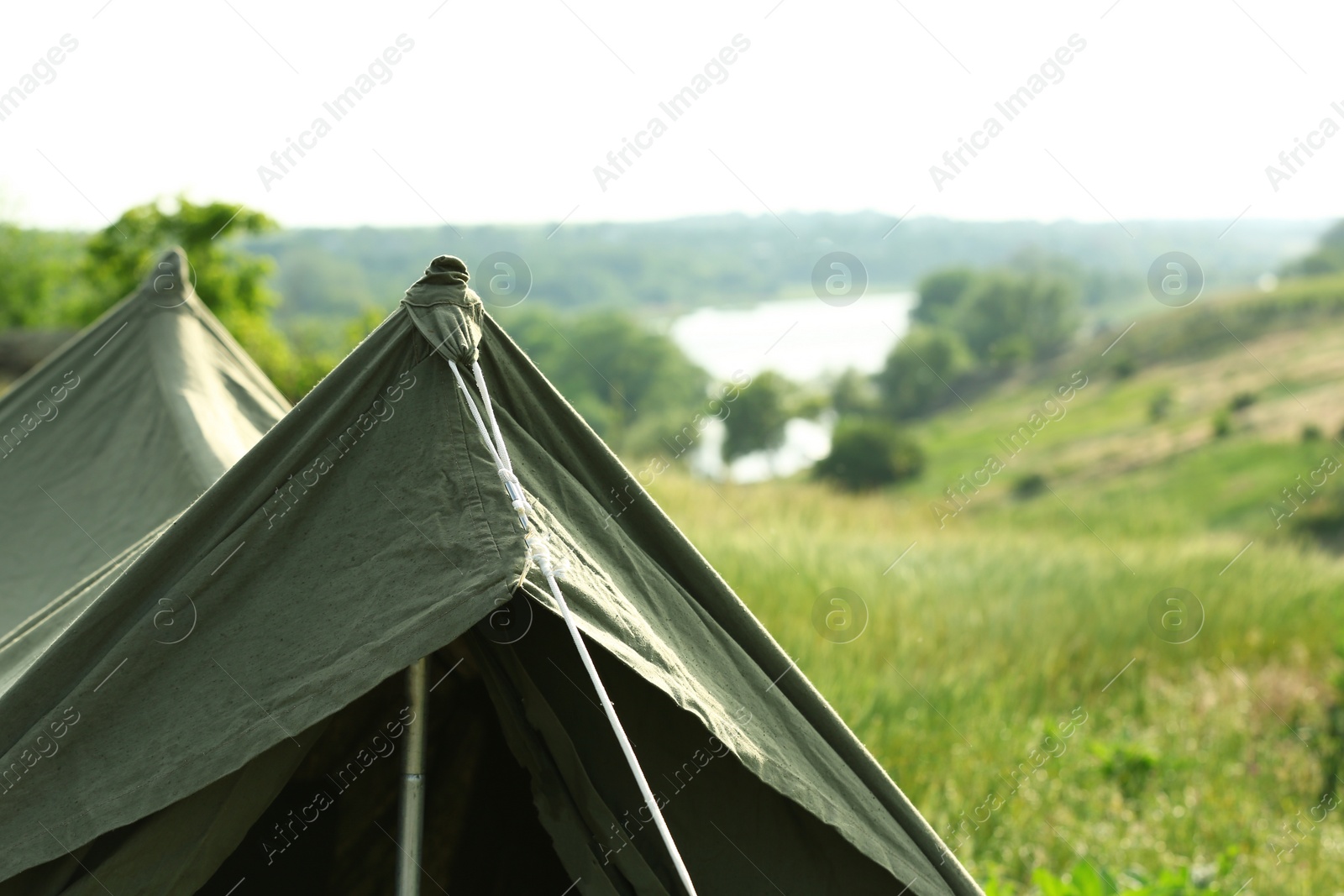 Photo of Camping tent in green field on sunny day. Space for text