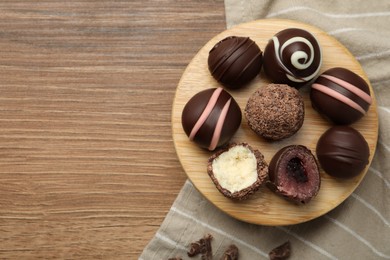 Photo of Many different delicious chocolate truffles on wooden table, top view. Space for text