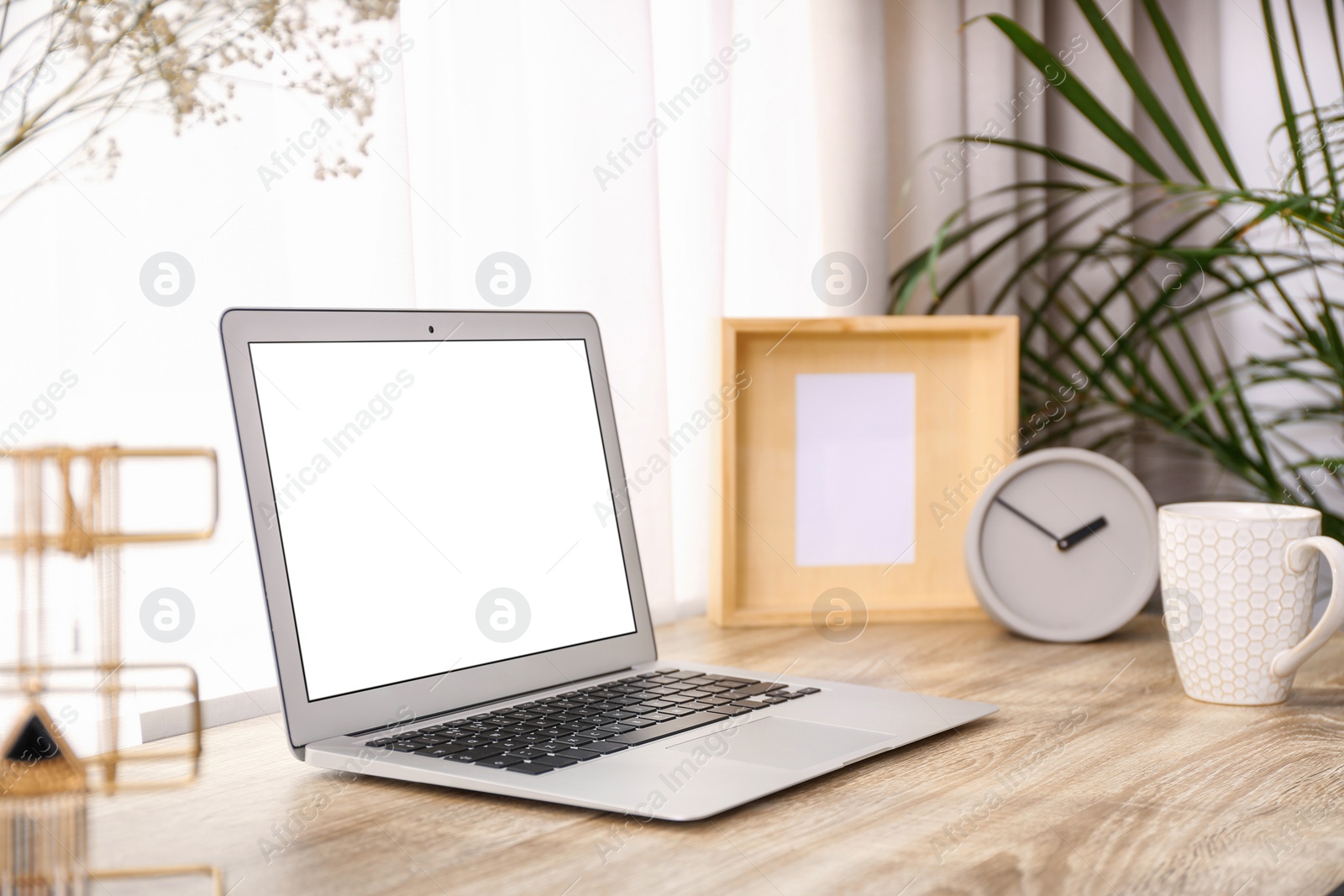 Photo of Stylish workplace interior with laptop on wooden table near window