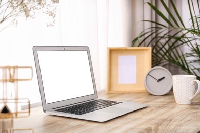 Photo of Stylish workplace interior with laptop on wooden table near window