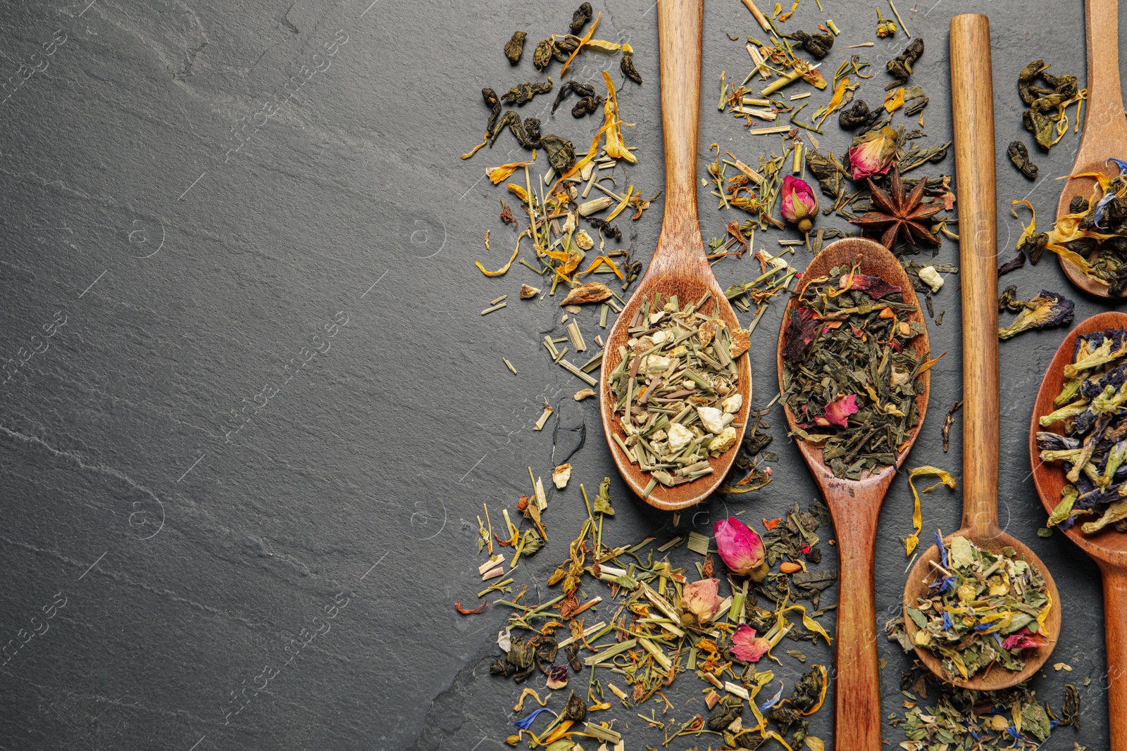 Photo of Wooden spoons with different teas on black table, flat lay. Space for text