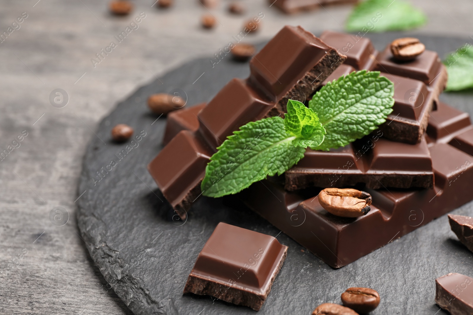 Photo of Pieces of dark chocolate with mint on slate plate