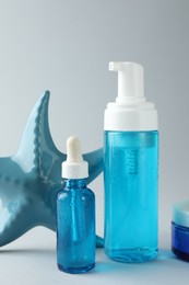 Set of cosmetic products and decorative starfish on light grey background