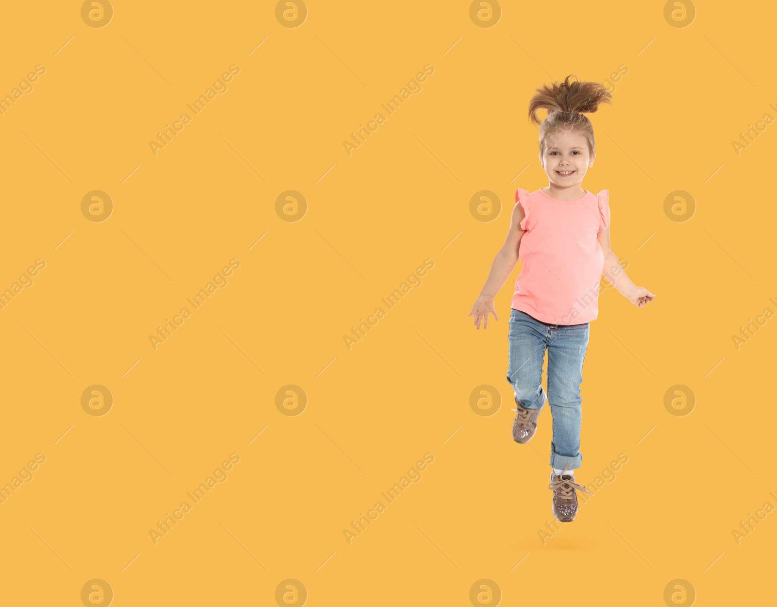 Image of Cute girl jumping on pale orange background, space for text