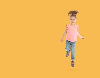 Cute girl jumping on pale orange background, space for text