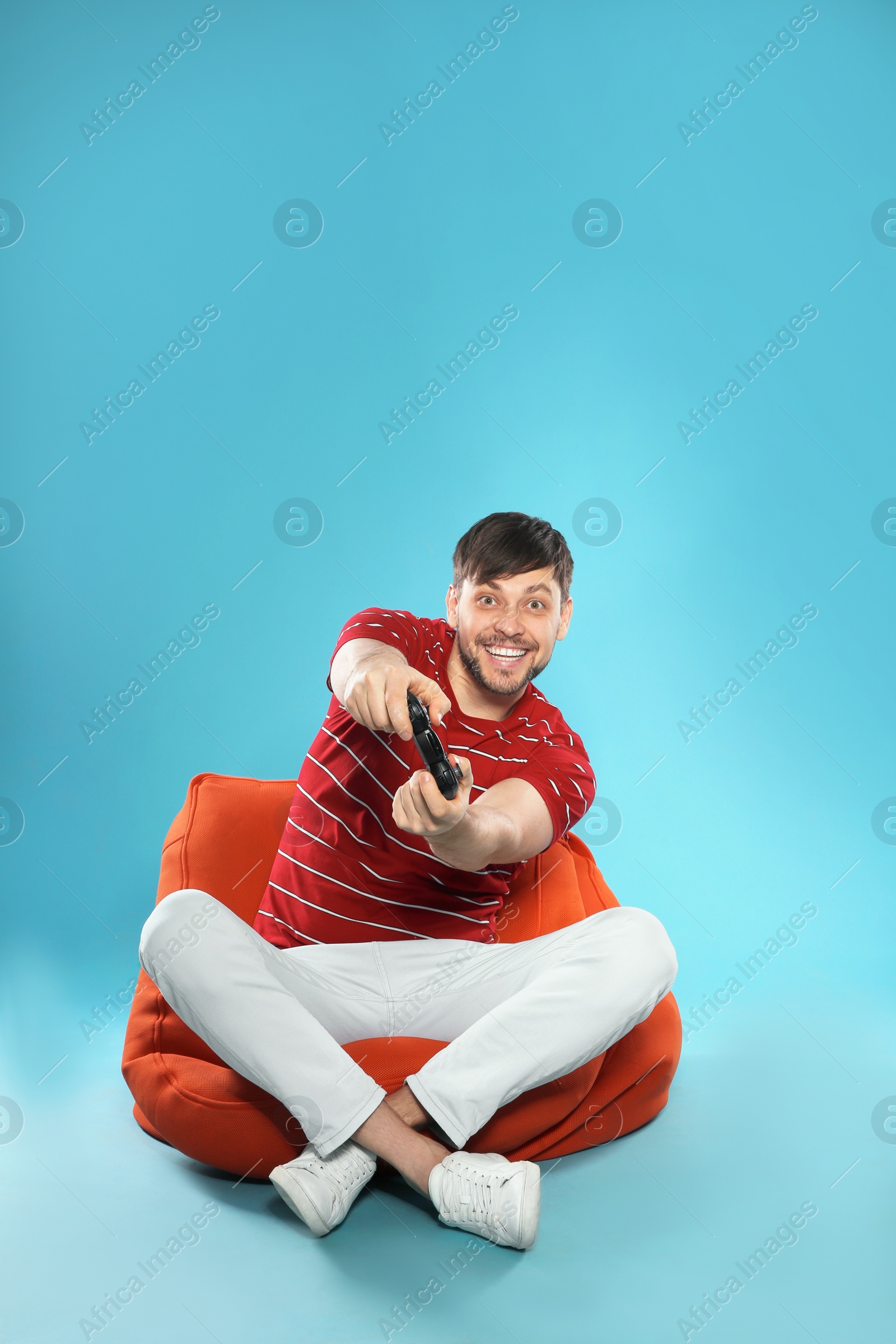 Photo of Emotional man playing video games with controller on color background. Space for text