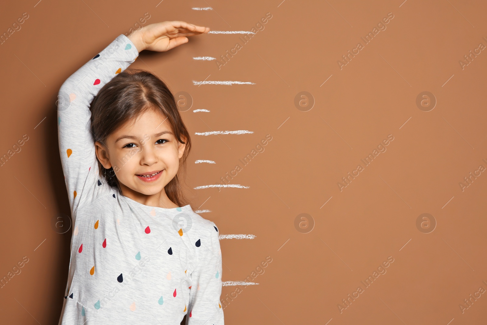 Photo of Little girl measuring her height on color background