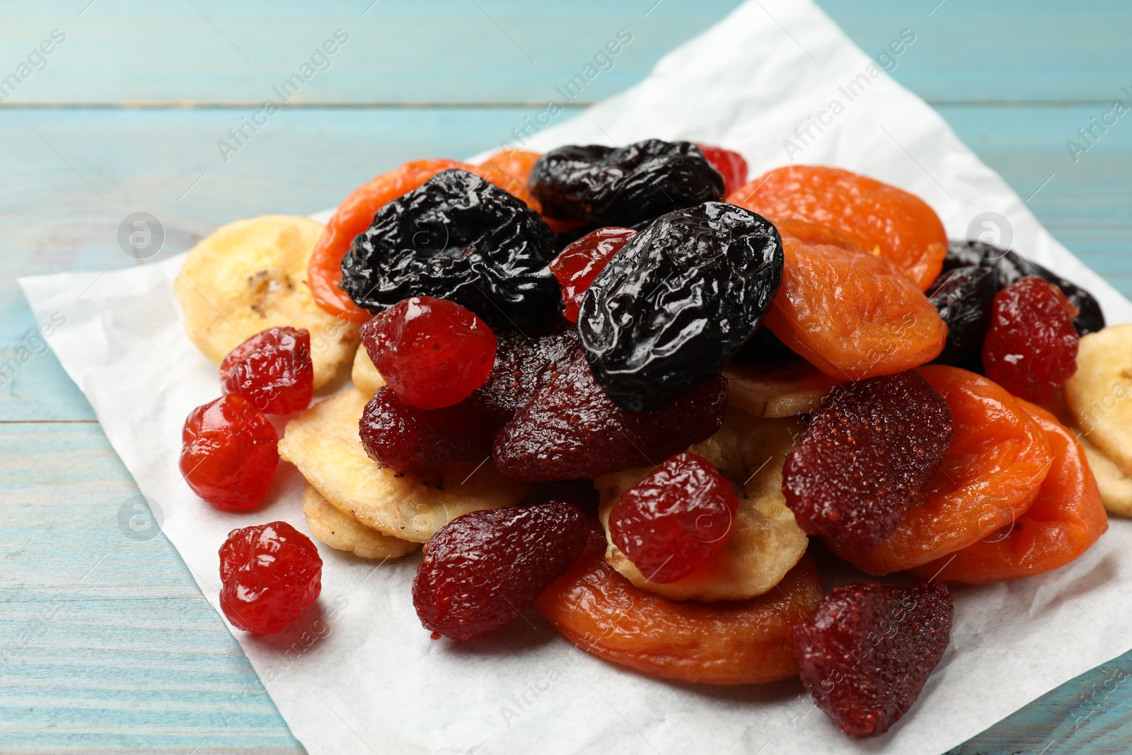 Photo of Mix of delicious dried fruits on light blue wooden table, closeup