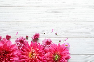 Photo of Flat lay composition with beautiful dahlia flowers and space for text on wooden background