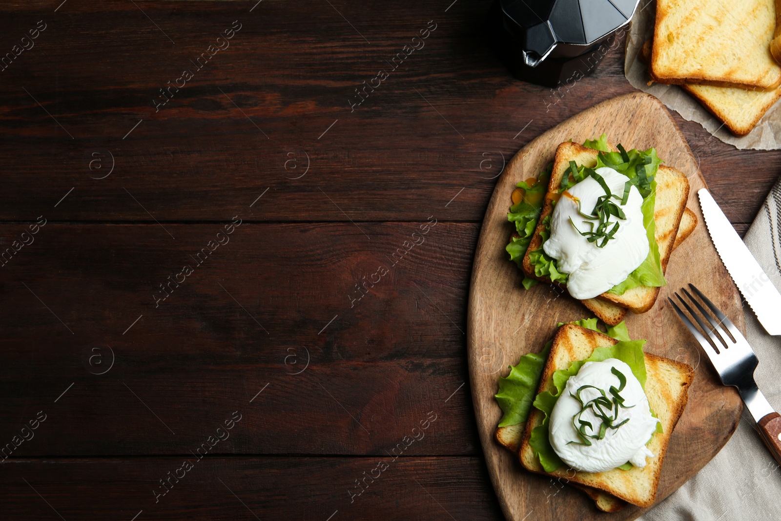 Photo of Delicious poached egg sandwiches served on wooden table, flat lay. Space for text