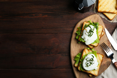 Photo of Delicious poached egg sandwiches served on wooden table, flat lay. Space for text