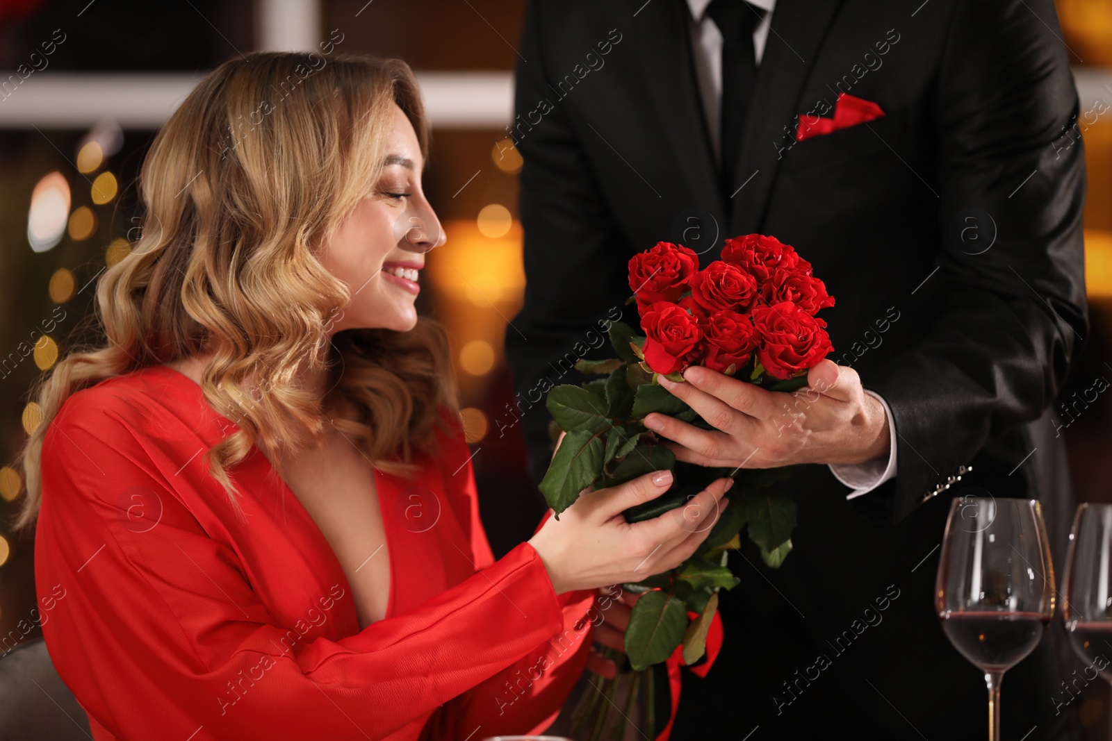 Photo of Man presenting roses to his beloved woman in restaurant at Valentine's day dinner