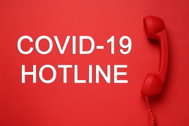 Image of Covid-19 Hotline. Handset and text on red background, top view