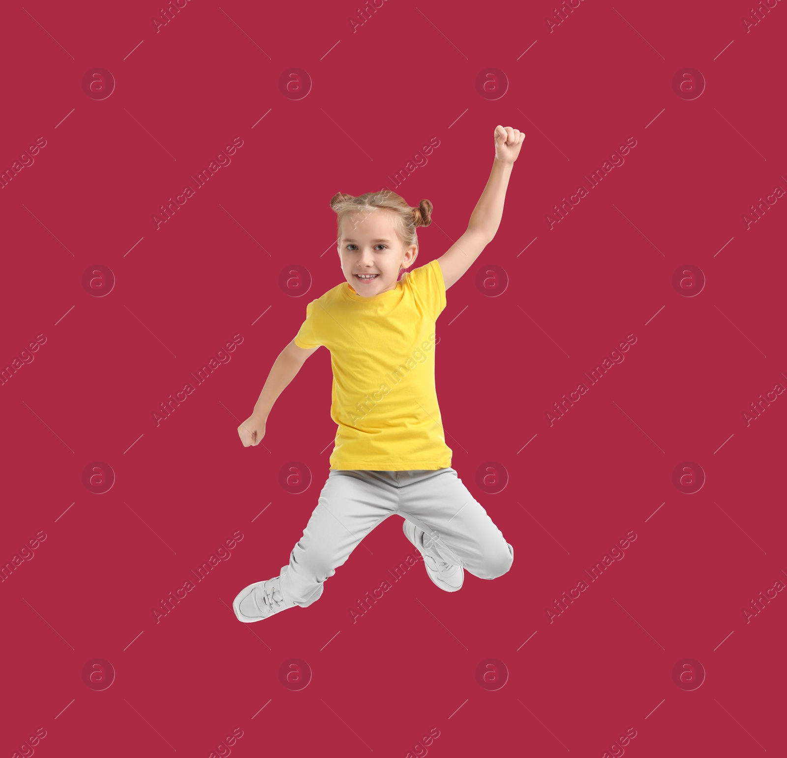 Image of Happy cute girl jumping on red background