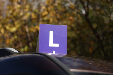 Photo of L-plate on car roof outdoors. Driving school