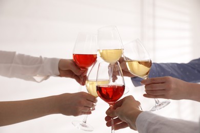 Photo of People clinking glasses of wine on white background, closeup