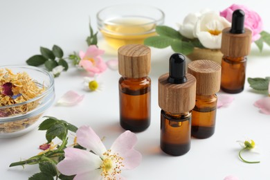 Photo of Aromatherapy. Essential oils and flowers on white table