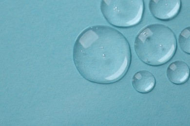 Drops of cosmetic serum on light blue background, top view. Space for text