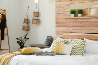 Photo of Stylish room interior with comfortable bed near wooden wall