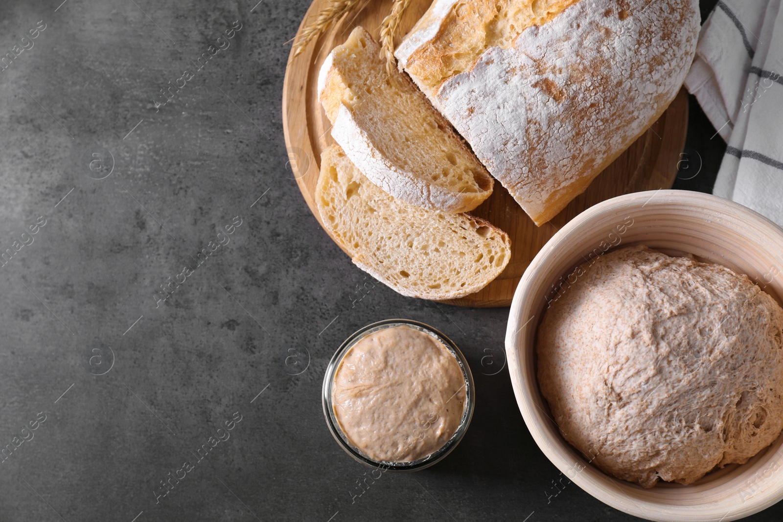 Photo of Fresh sourdough starter, dough and bread on grey table, top view. Space for text
